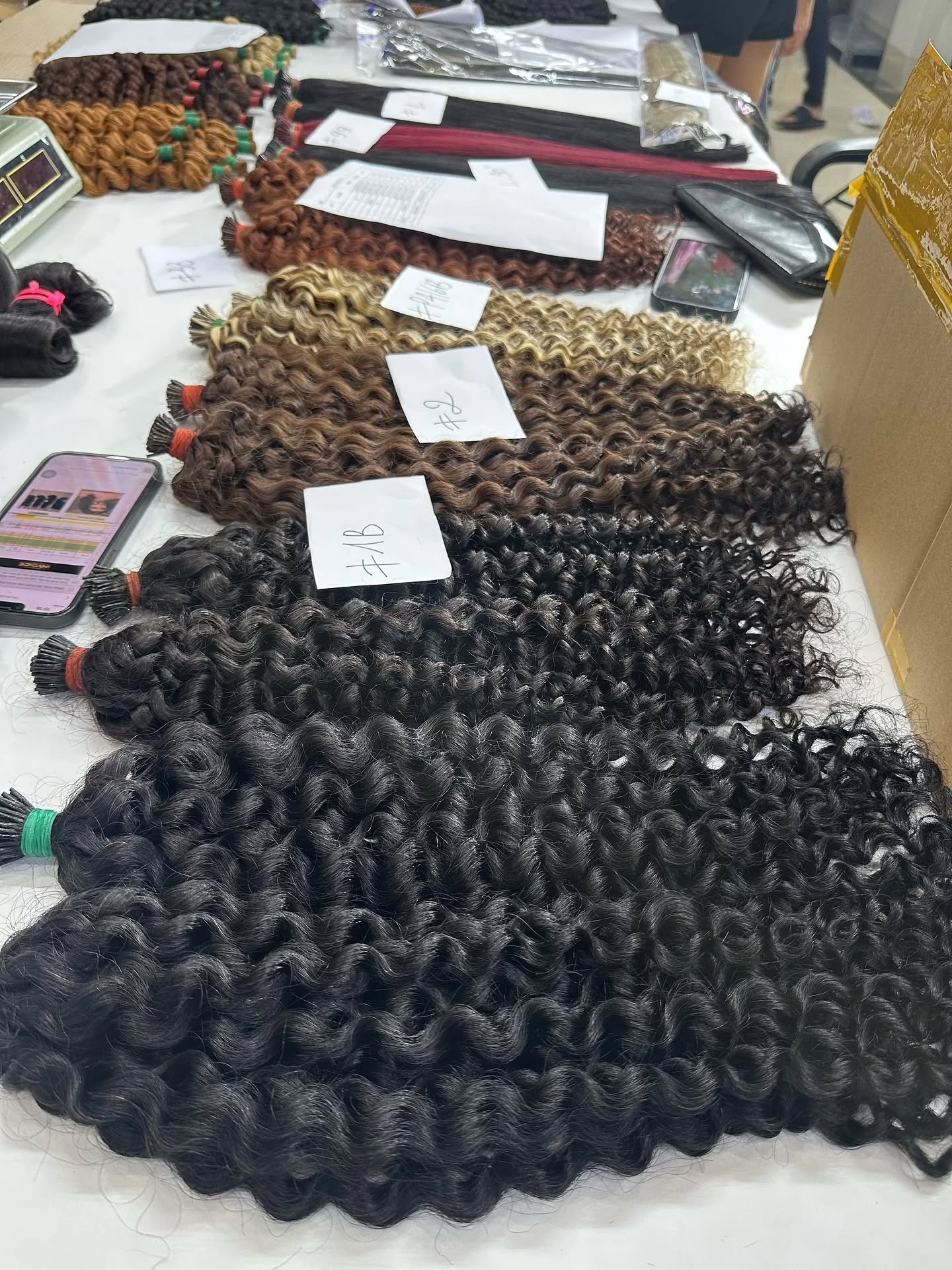 Vietnamese I-tip extensions showing keratin tips in multiple colors and curly textures